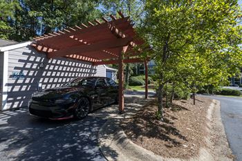 a car parked in a driveway under a wooden shade